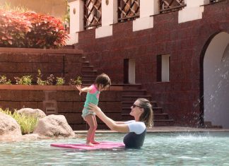 Bring home vacation photos you’re actually in! Mother helps daughter balance on a body board in a pool while on vacation