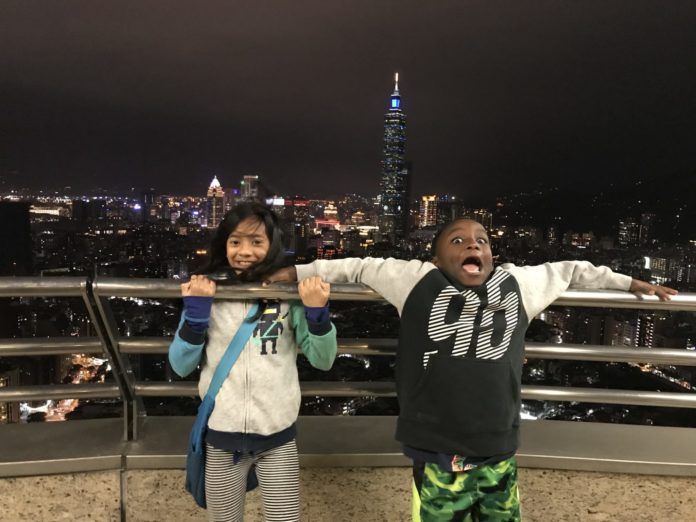 Two excited children have fun on the balcony of a skyscraper.