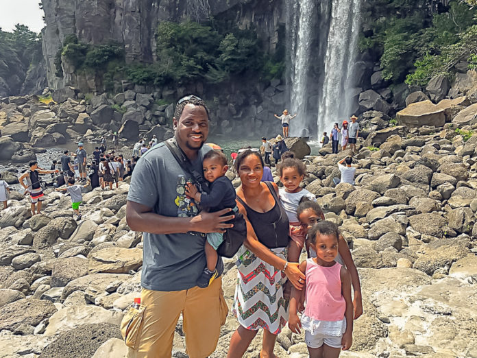 Family of 5 stands in front of a large waterfall on juju island