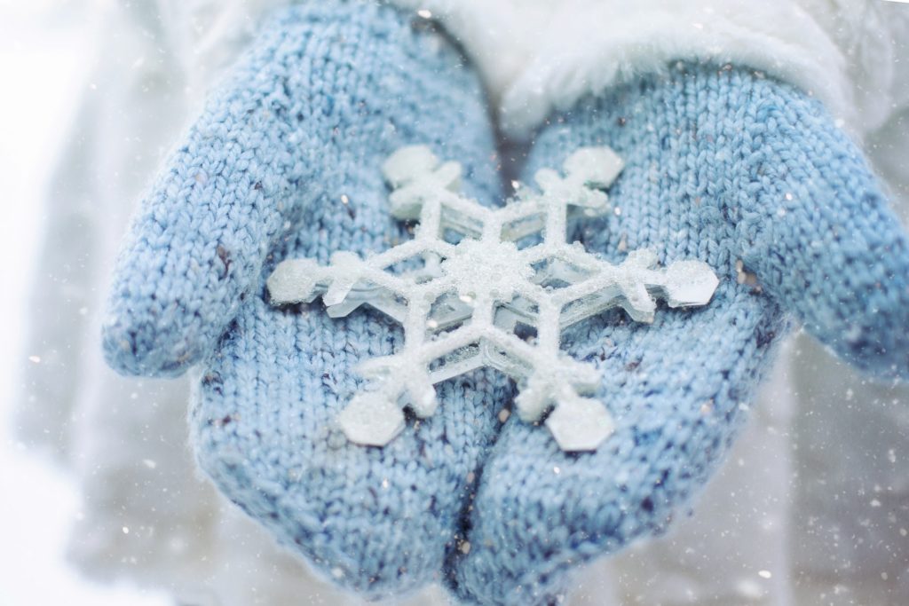Pair of mittens holding an oversized snowflake