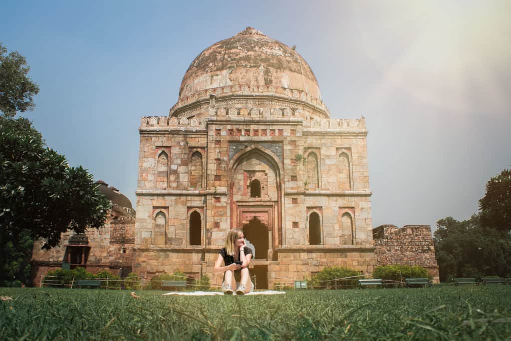 What to wear in India. Woamn sits in front of large monument in New Delhi