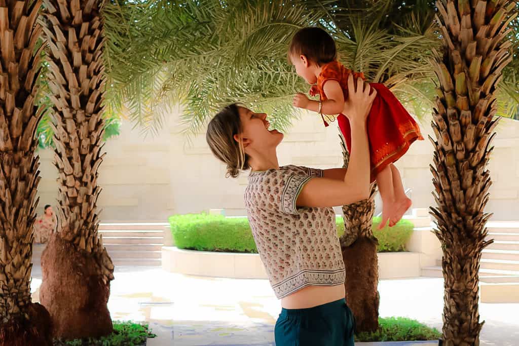 Mother holds toddler up above her head in Delhi India, wearing a crop top