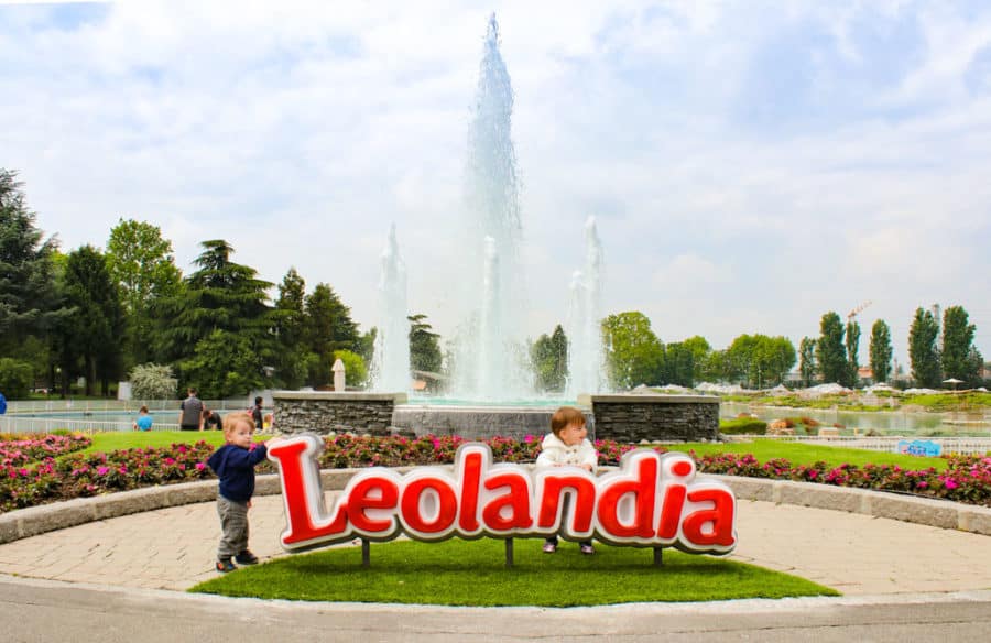 Two toddler stands next to Leolandia sign in Italy