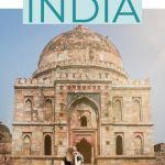 Woman sits in front of monument in new delhi wearing shorts