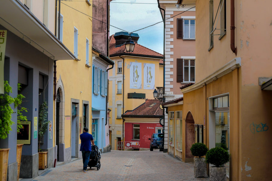 Man pushes a stroller down a cobblestone street in Locarno