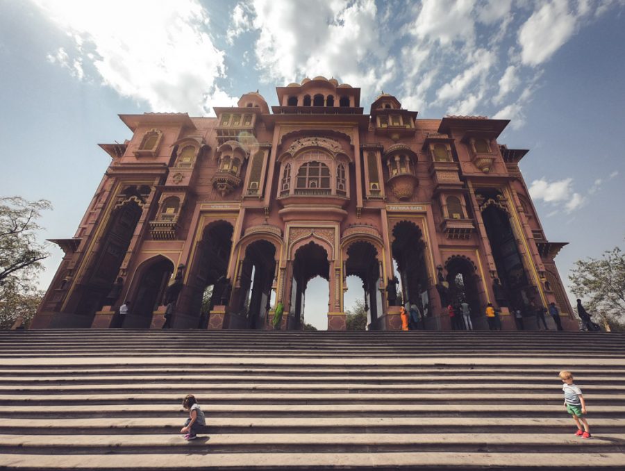 Toddlers play on the steps of a large gate in Jaipur, India