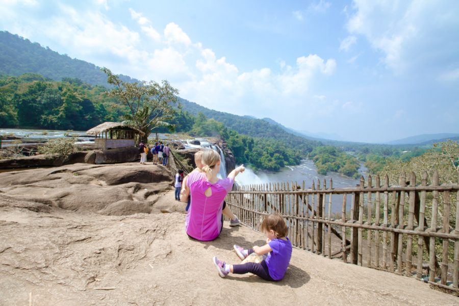 Mother and toddlers sit at a lookout over a large waterfall in Kerala
