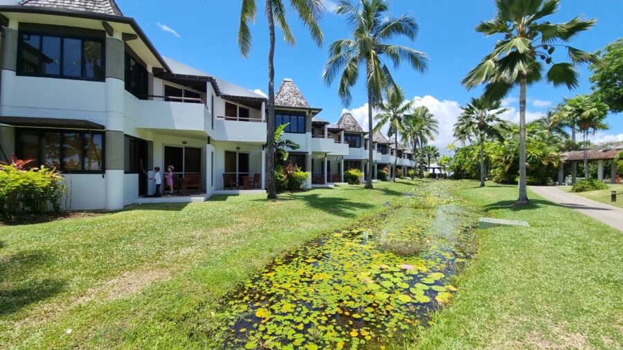 Hotel rooms to left of image. Palm trees and a pond located in Fiji. 