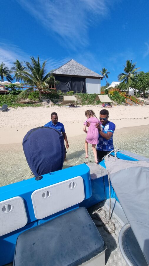 Child is lifted off of a speedboat on arrival at a Fiji family holiday. 