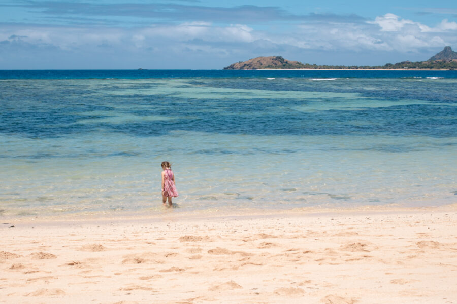 Child wades through clear water at a family friendly resort in Fiji. 
